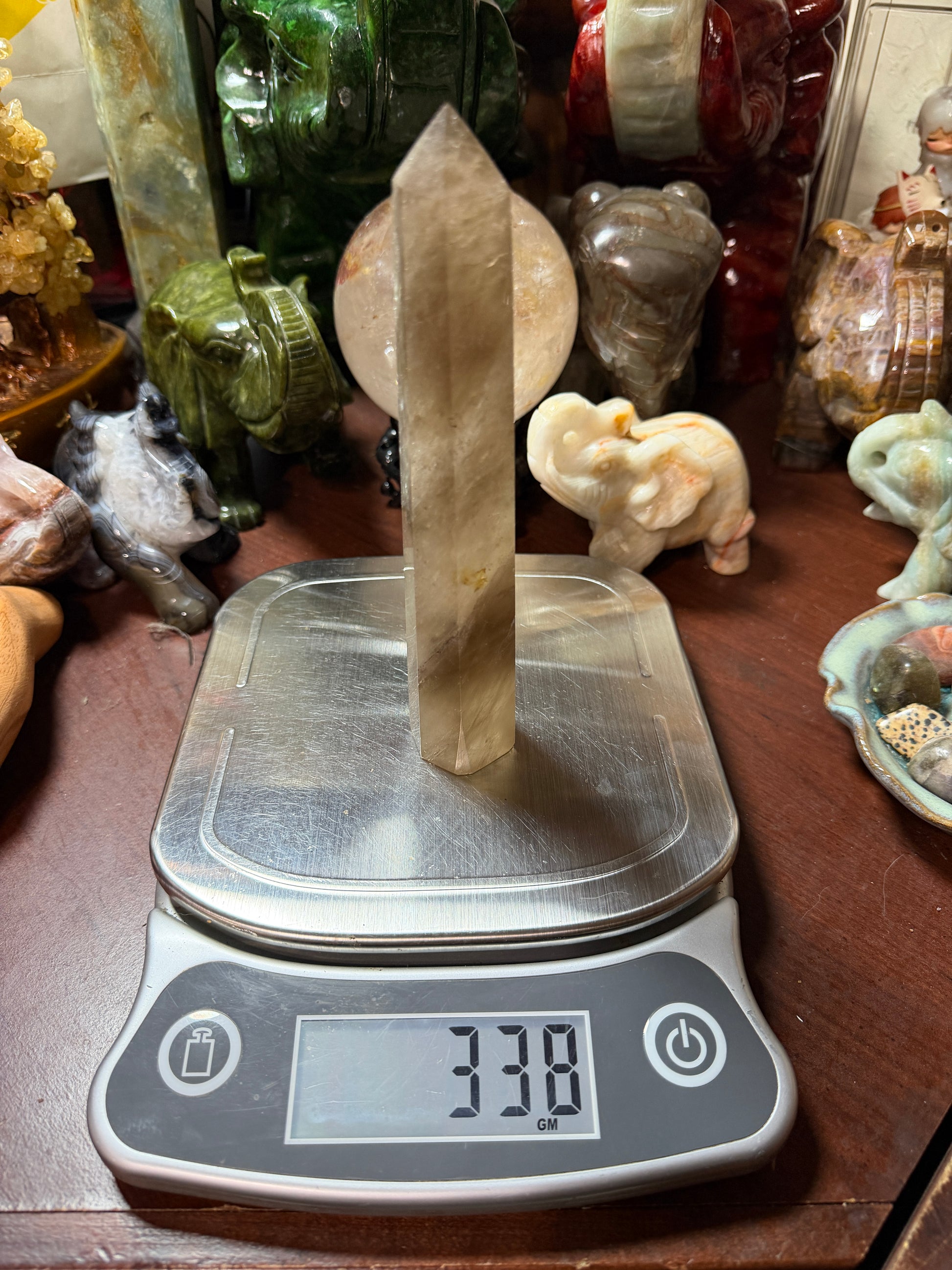 Smoky quartz crystal tower on digital scale showing weight